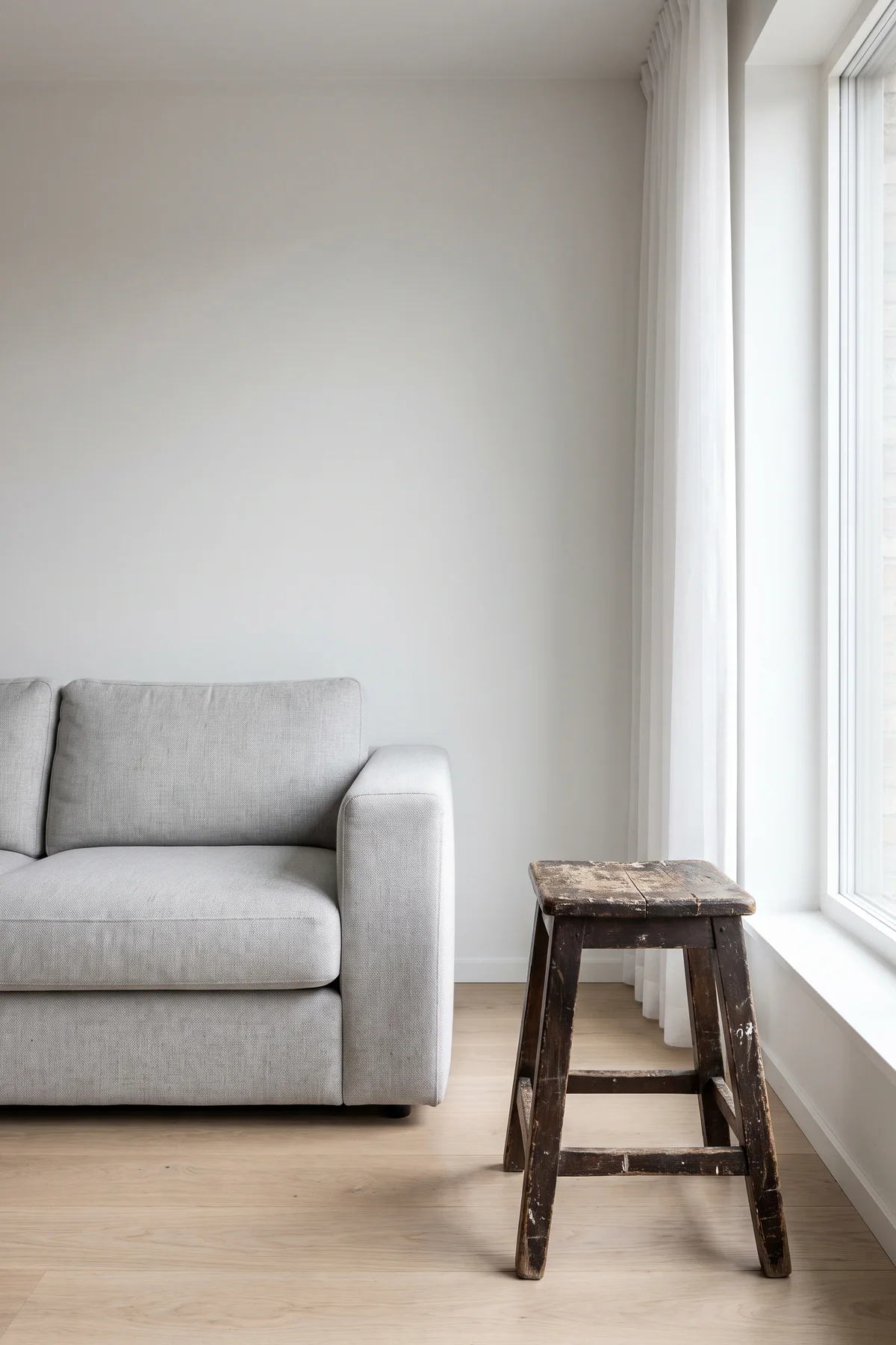 Scuffed wooden stool beside a grey sofa before AI interior object replacement